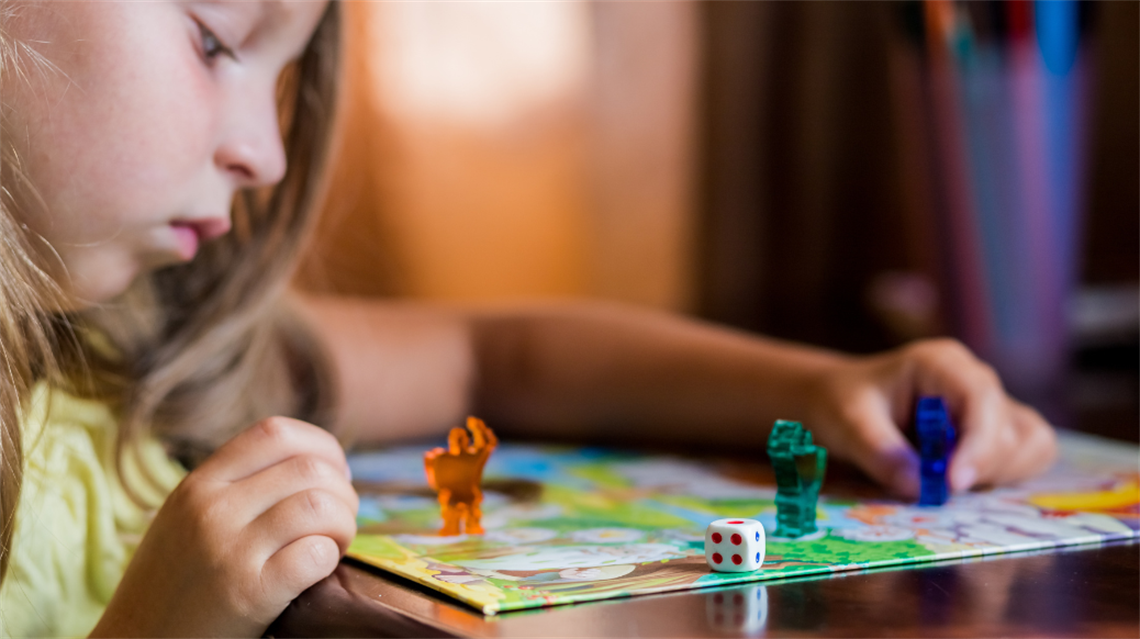 Young girl focused on board game on table