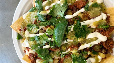 Aerial view of nachos in a bowl with a lime wedge and cilantro