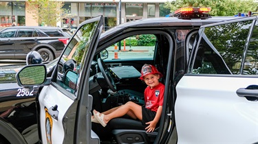 Young boy sitting inside a police car and smiling