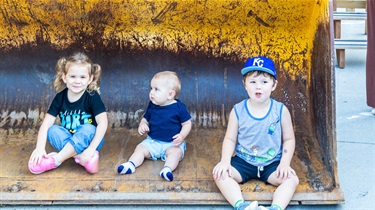 Three kids sitting inside snow plow pusher