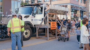 Snow plow in training sign on City vehicle with kids touring it