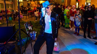 Woman dressed as a musician and performer wearing white gloves and black hat for Halloween themed Friday Night Sound Bites