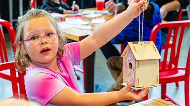 Girl proudly holding her colored bird house