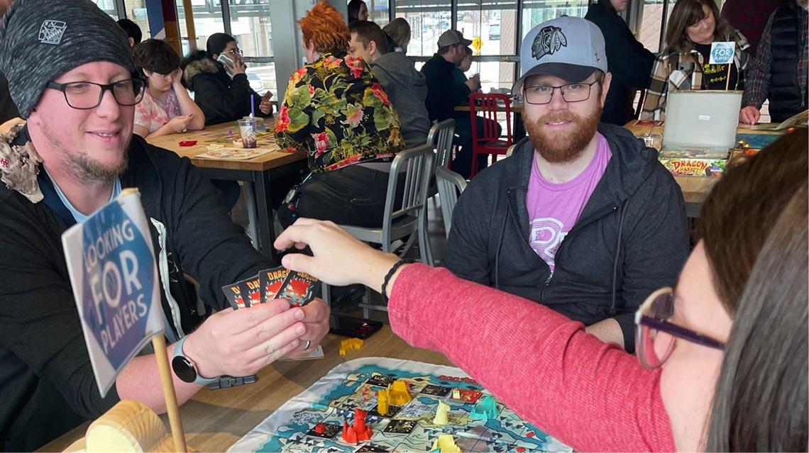 Three people at table playing board game