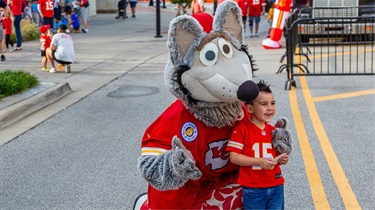 Kanas City Chiefs mascot posing with smiling young boy outside the Public Market