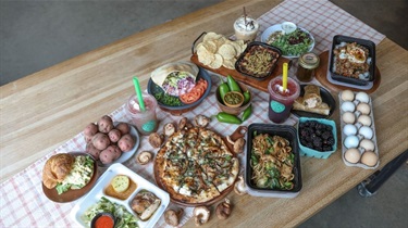 Table spread of Farm to Fork dishes on wooden table with fresh ingredients from the Farmers Market