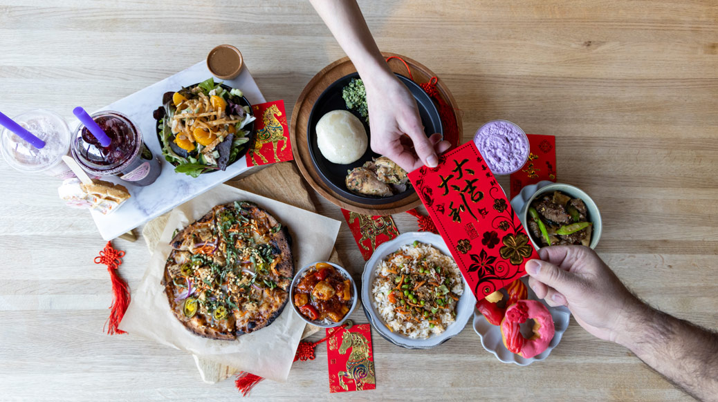 Two hands grabbing opposite ends of Chinese red envelope and merchant food specials plated beneath 