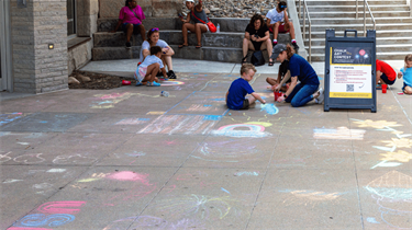 Kids and adults participating in a chalk art contest outside the Public Market