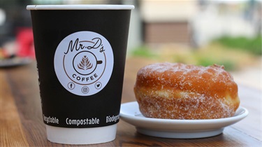 Mr. D's hot beverage and donut sitting on table outside the Public Market