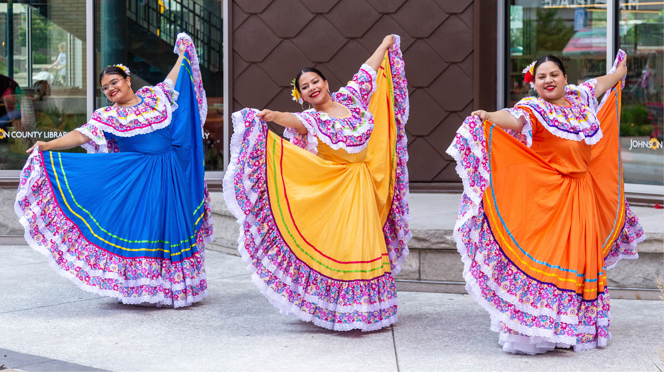 Three ladies wearing traditional Mexican dresses performing outside the Lenexa Public Market