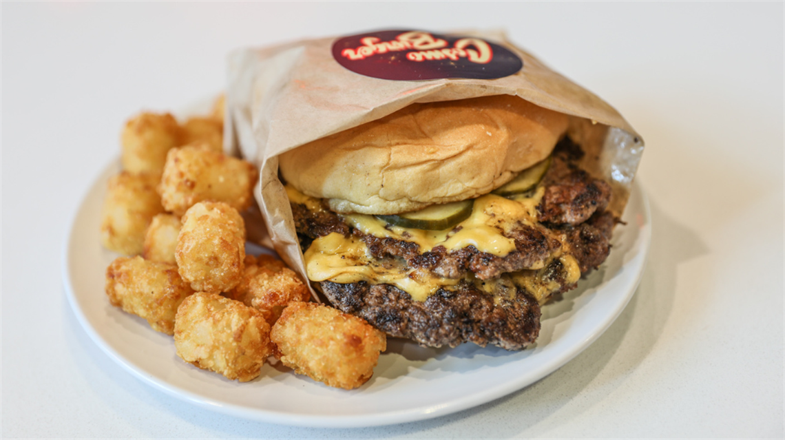Burger and tots from Cosmo Burger on a white plate