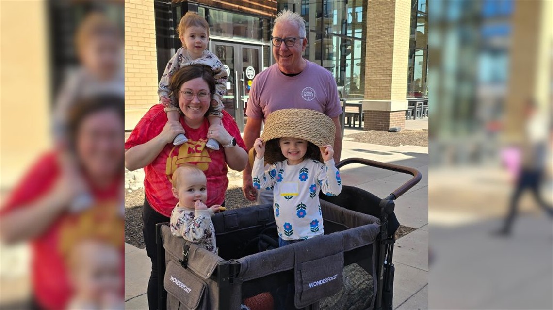 Erica B. with her three kiddos and Tom, Public Market concierge, smiling outisde the Public Market