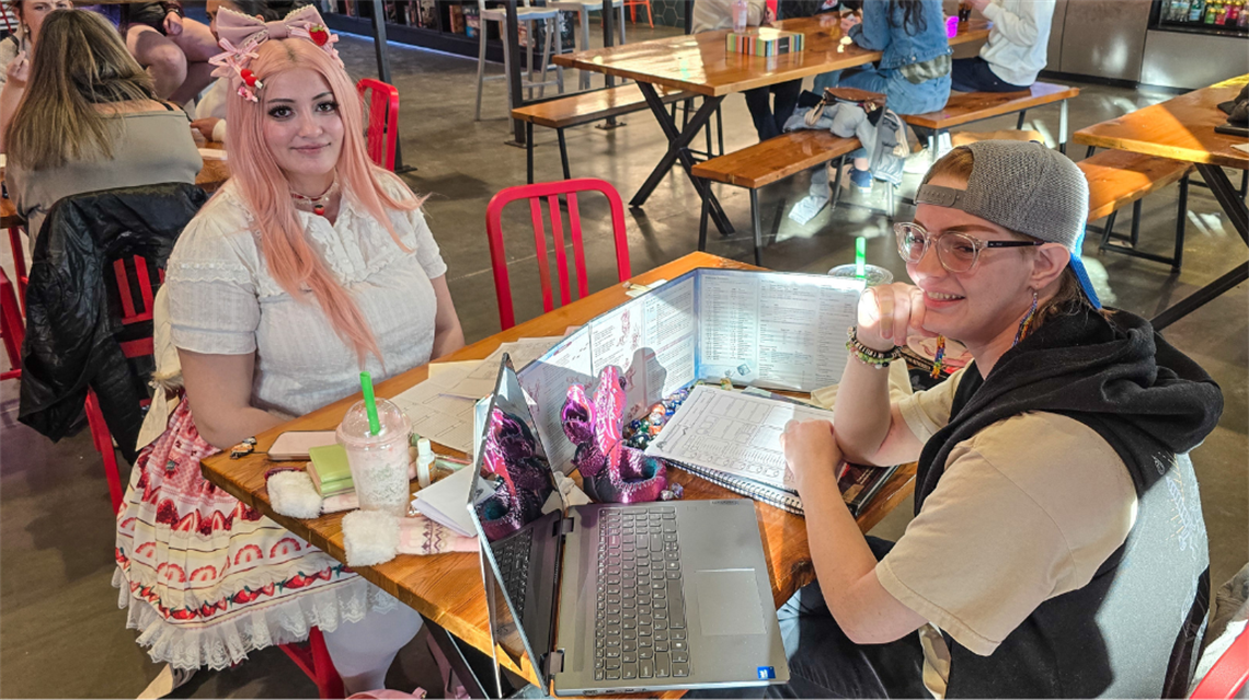 Ellie and Avail sitting at table with game set up inside the Public Market