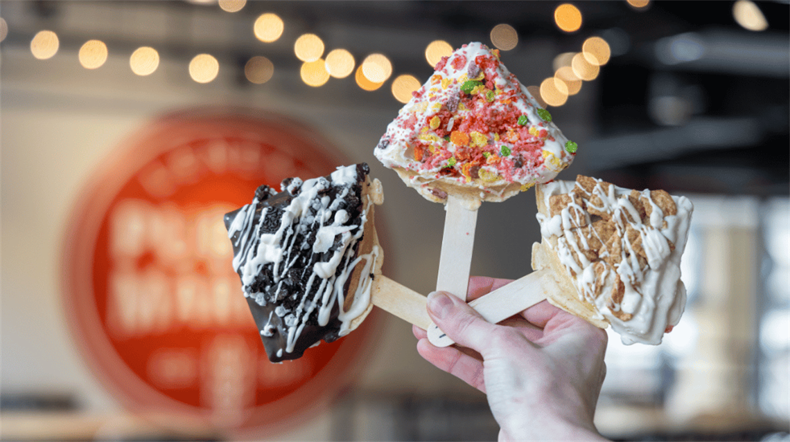 Wafflepop from Cardboard Corner Cafe coated in colorful cereal with Public Market logo in background
