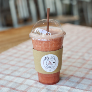 Elderberry latte and watermelon smoothie on top of fabric runner sitting on wooden table